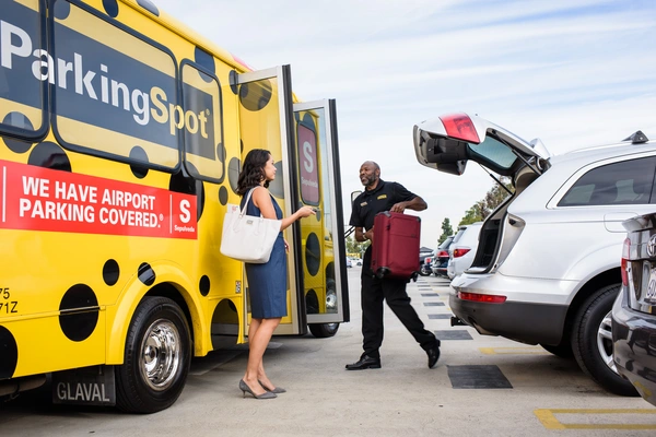 The Parking Spot airport shuttle driver helps a guest load luggage